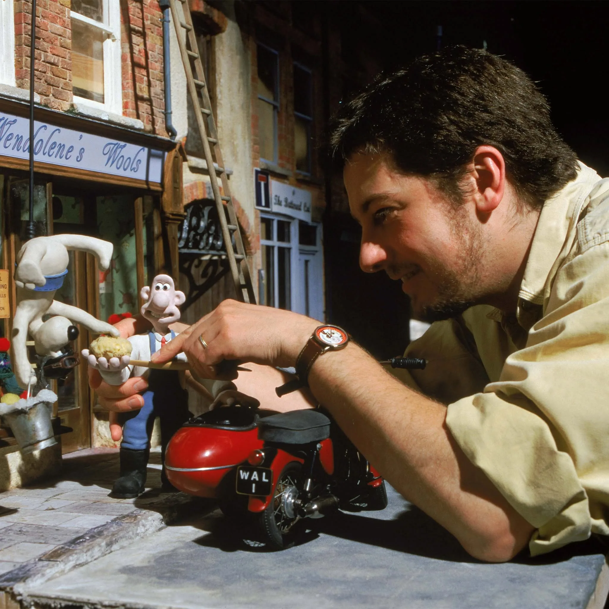 Loyd Price adjusts Wallace and Gromit beside the red motorbike on the Wendolene’s Wools set of A Close Shave.