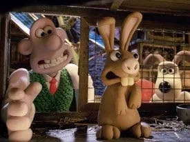 Wallace reaches toward a rabbit while Gromit looks through wire mesh in The Curse of the Were-Rabbit.